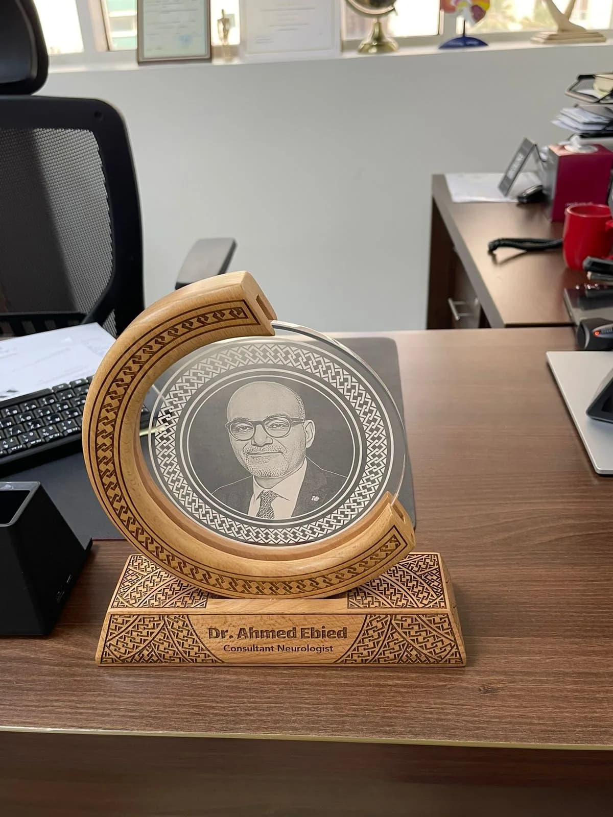 A personalized desk plaque recognizing Dr. Ahmed Ebied, Consultant Neurologist.